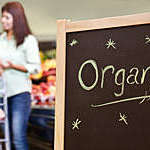 Organic sign in a grocery store with shoppers in the background.