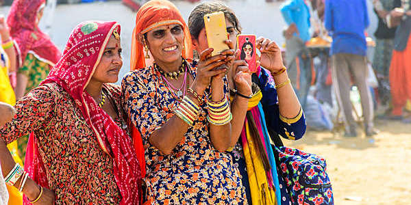 Three Indian women staring at a smartphone.