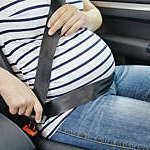 Close-up of pregnant woman buckling up in her car.