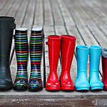 Front view of five pairs of colourful rain boots lined in a row.