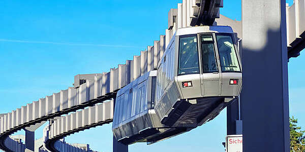 A grey suspension train meanders along a steel monorail at Düsseldorf International Airport, Germany.