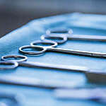Close-up of three pairs of surgical scissors laid out on a blue sterilization wrap.