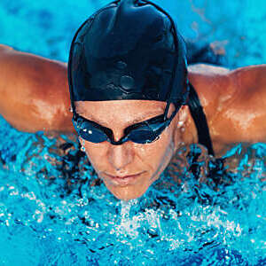  Woman wearing swimming goggles, swimming in a pool.