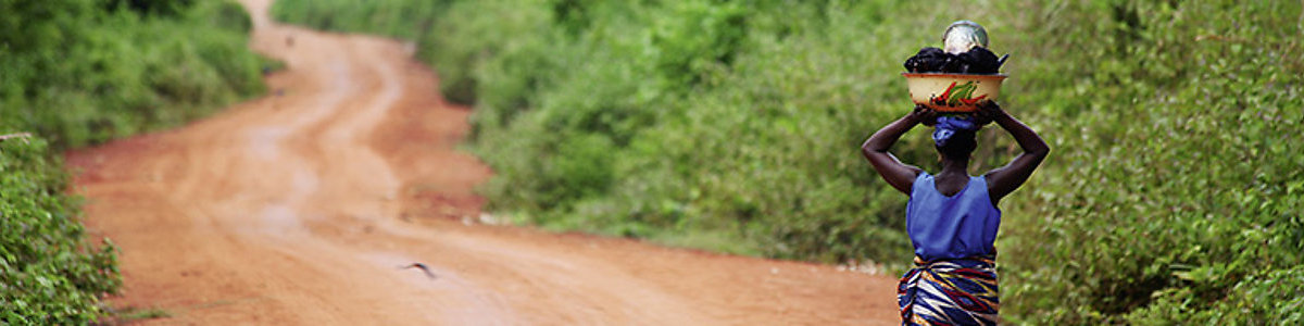 African woman carrying a basket on a road